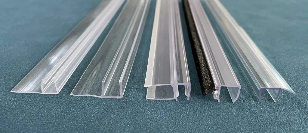 A close-up view of different types of shower door seals in various profiles and materials, displayed on a blue surface. | ACE DECOR