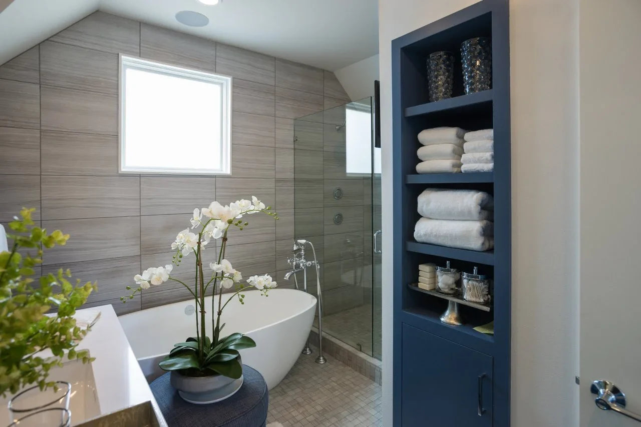 This modern bathroom features a sleek freestanding tub and a stylish tall bathroom storage cabinet built in with neatly organized towels and decor. | ACE DECOR