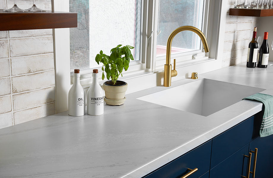 a modern kitchen countertop with a sleek laminate surface, showcasing a clean, minimalist design with a white sink and gold faucet. | ACE DECOR