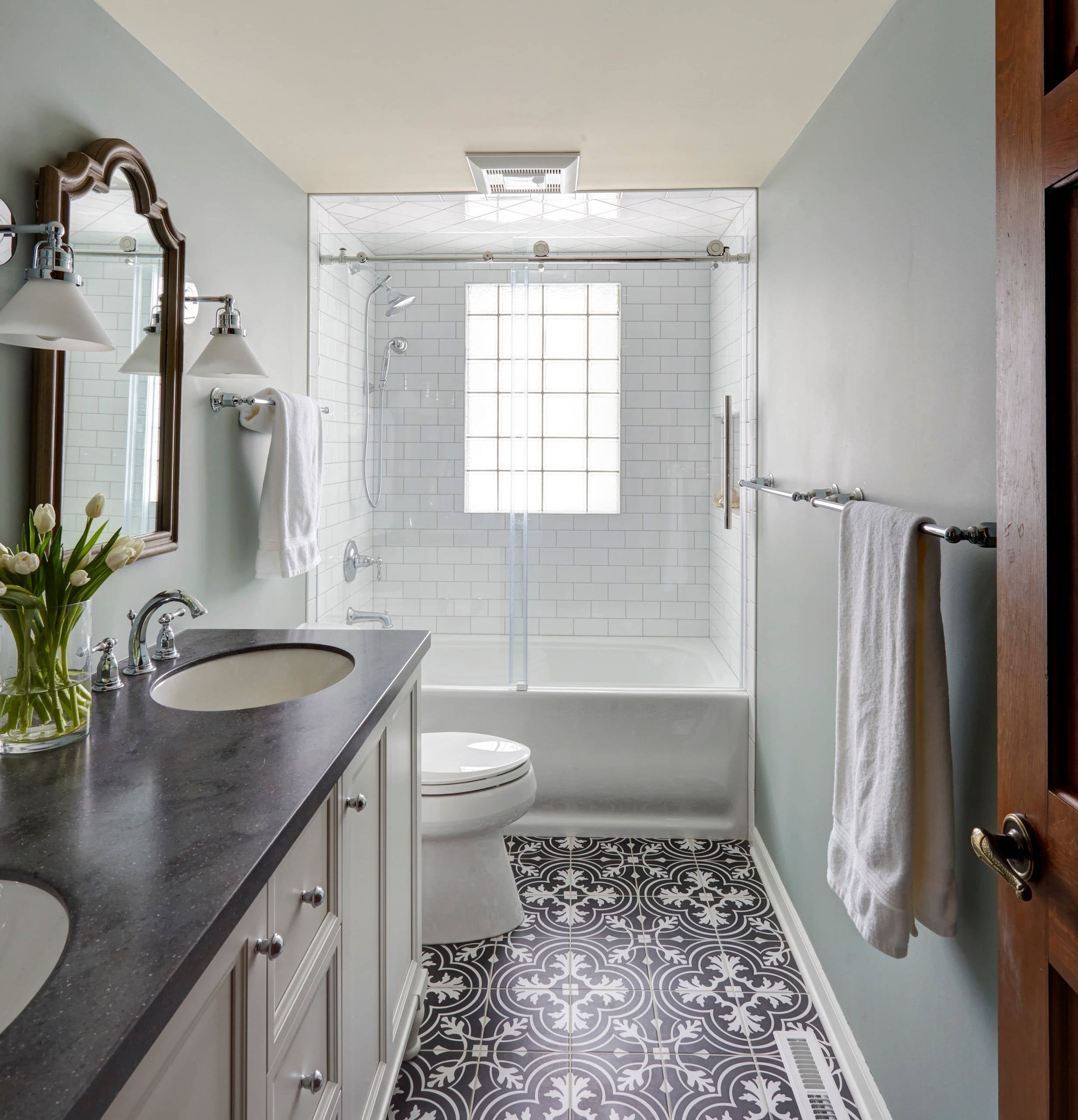 A clean and modern bathroom featuring a bathtub with a glass shower enclosure, subway tiles, and elegant flooring. |ACE DECOR