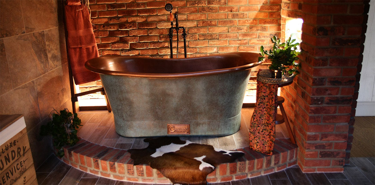 a copper bathtub in a rustic bathroom setting, featuring exposed brick walls, warm lighting, and vintage-inspired décor for a cozy, luxurious ambiance. | ACE DECOR
