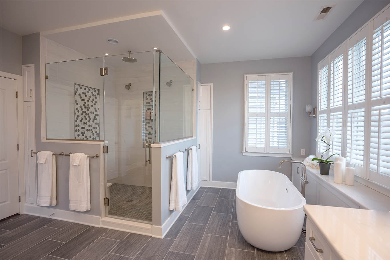 a modern bathroom with a luxurious freestanding tub and a glass pivot shower door, showcasing clean lines and elegant finishes. | ACE DECOR