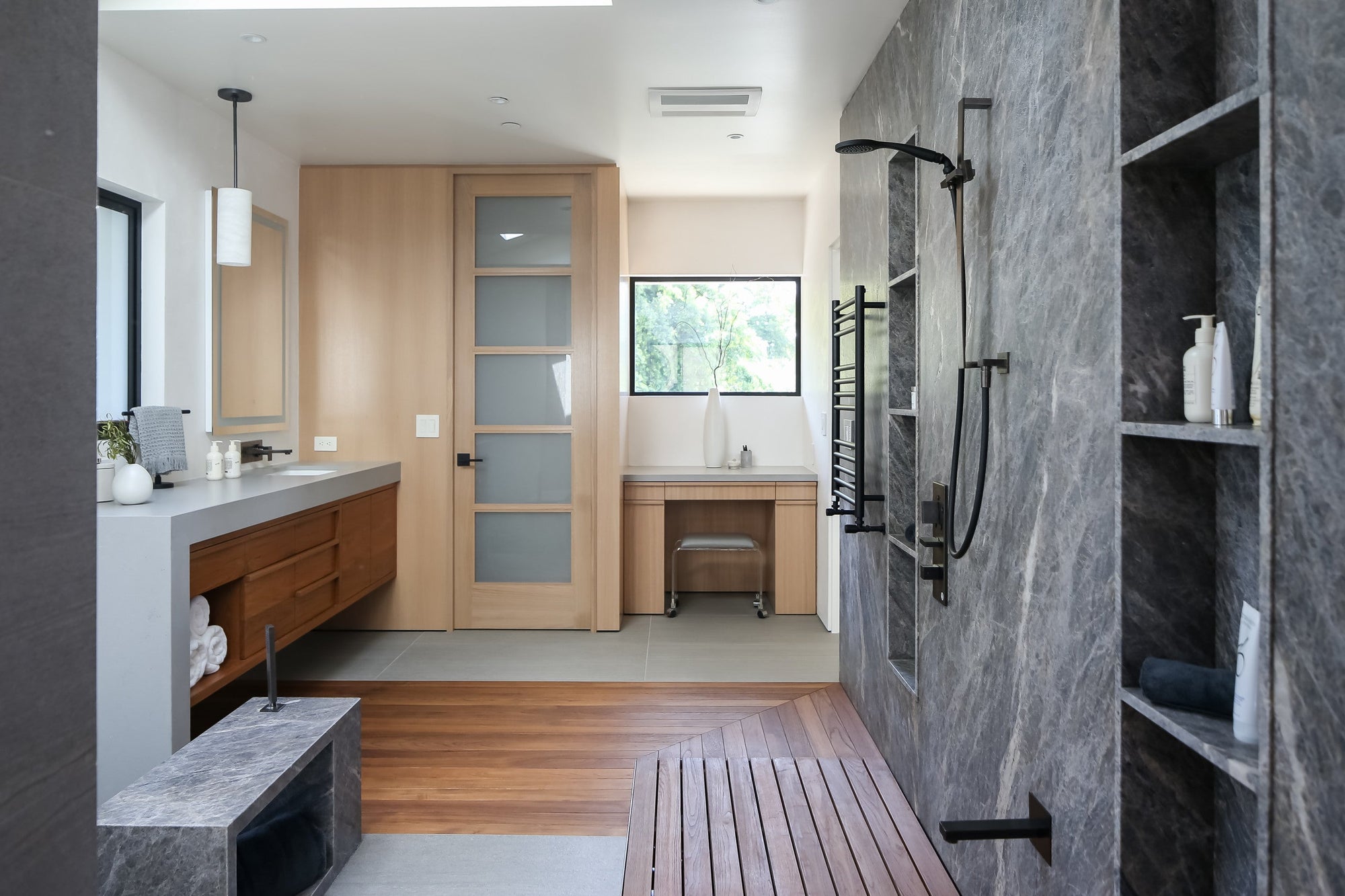 A modern, spa-inspired bathroom featuring a sleek walk-in shower with dark stone walls, wood accents, and minimalist design touches. | ACE DECOR 