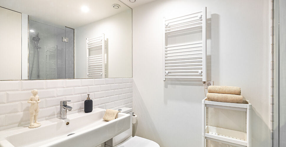 a modern bathroom with a Heated Towel Rack Electric mounted on the wall, holding neatly folded towels. | ACE DECOR