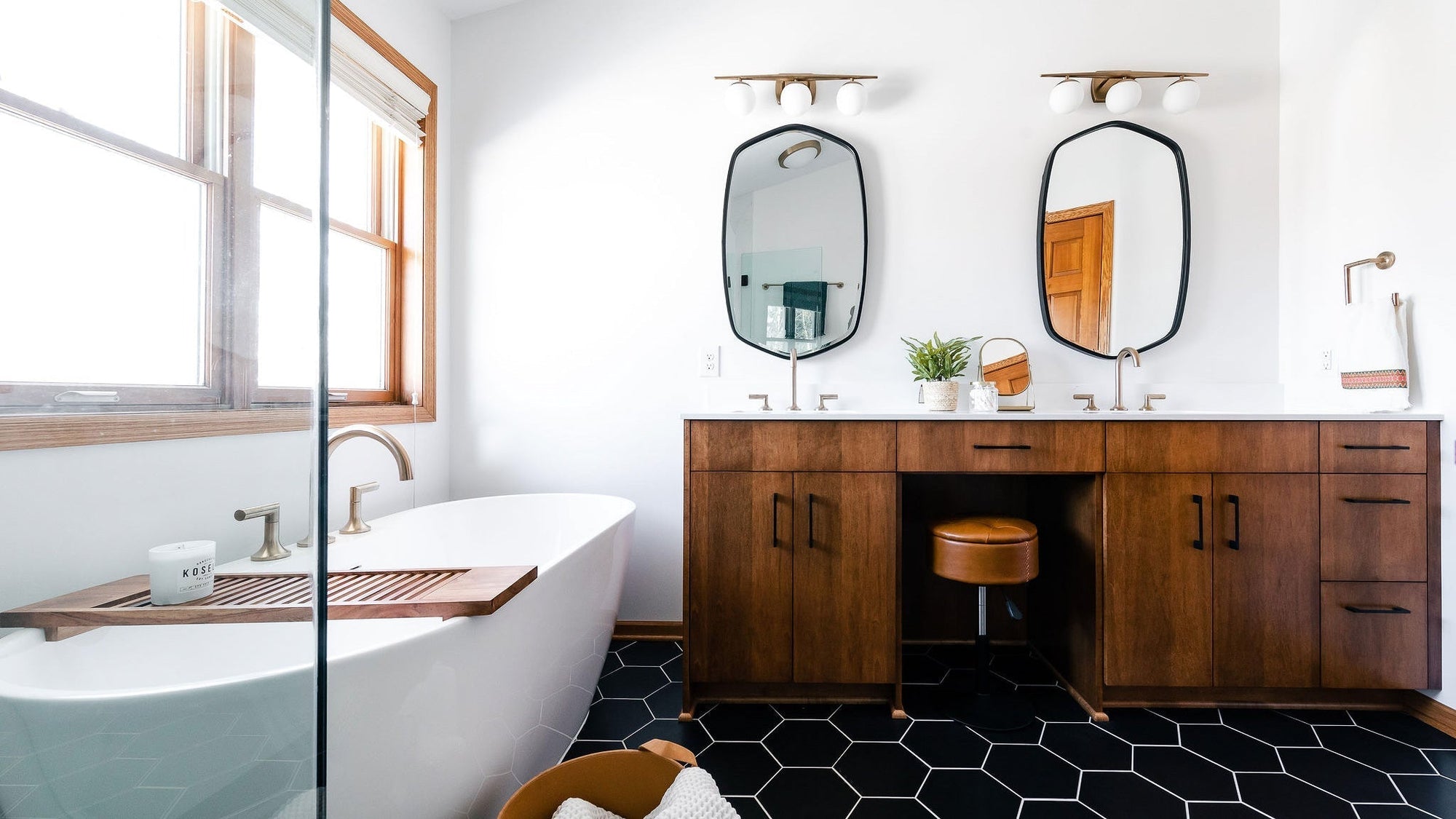 A modern bathroom with a sleek design, featuring a wooden vanity, black hexagonal floor tiles, and a freestanding bathtub. | ACE DECOR