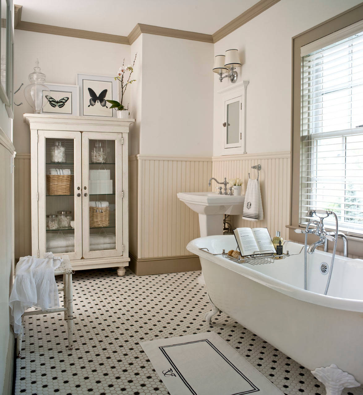 A bright vintage bathroom featuring bathrooms with white cabinets, a clawfoot tub, and classic black-and-white tiled flooring. | ACE DECOR