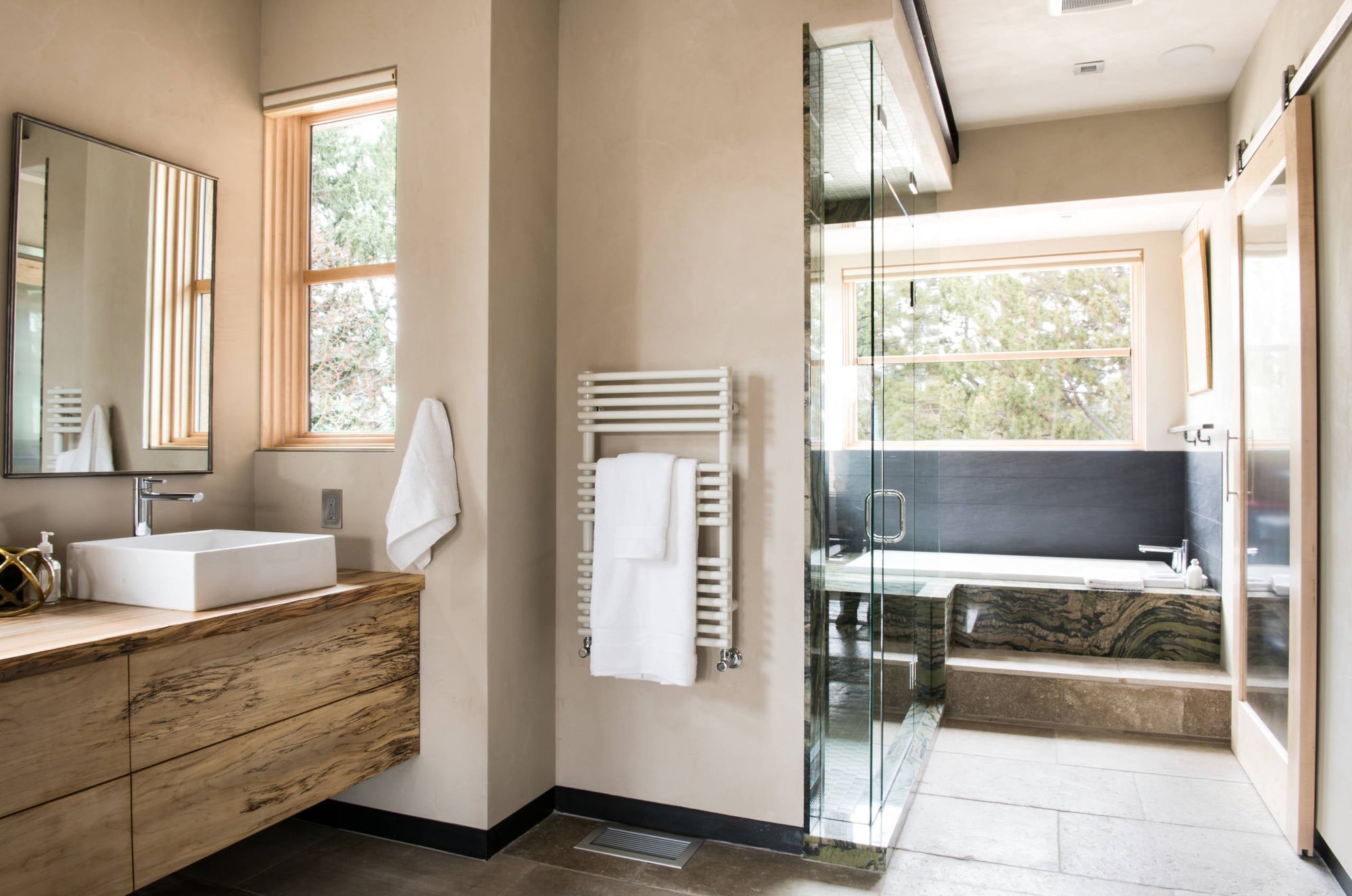 A stylish modern bathroom featuring a wall-mounted heated towel rack and natural wood accents. | ACE DECOR