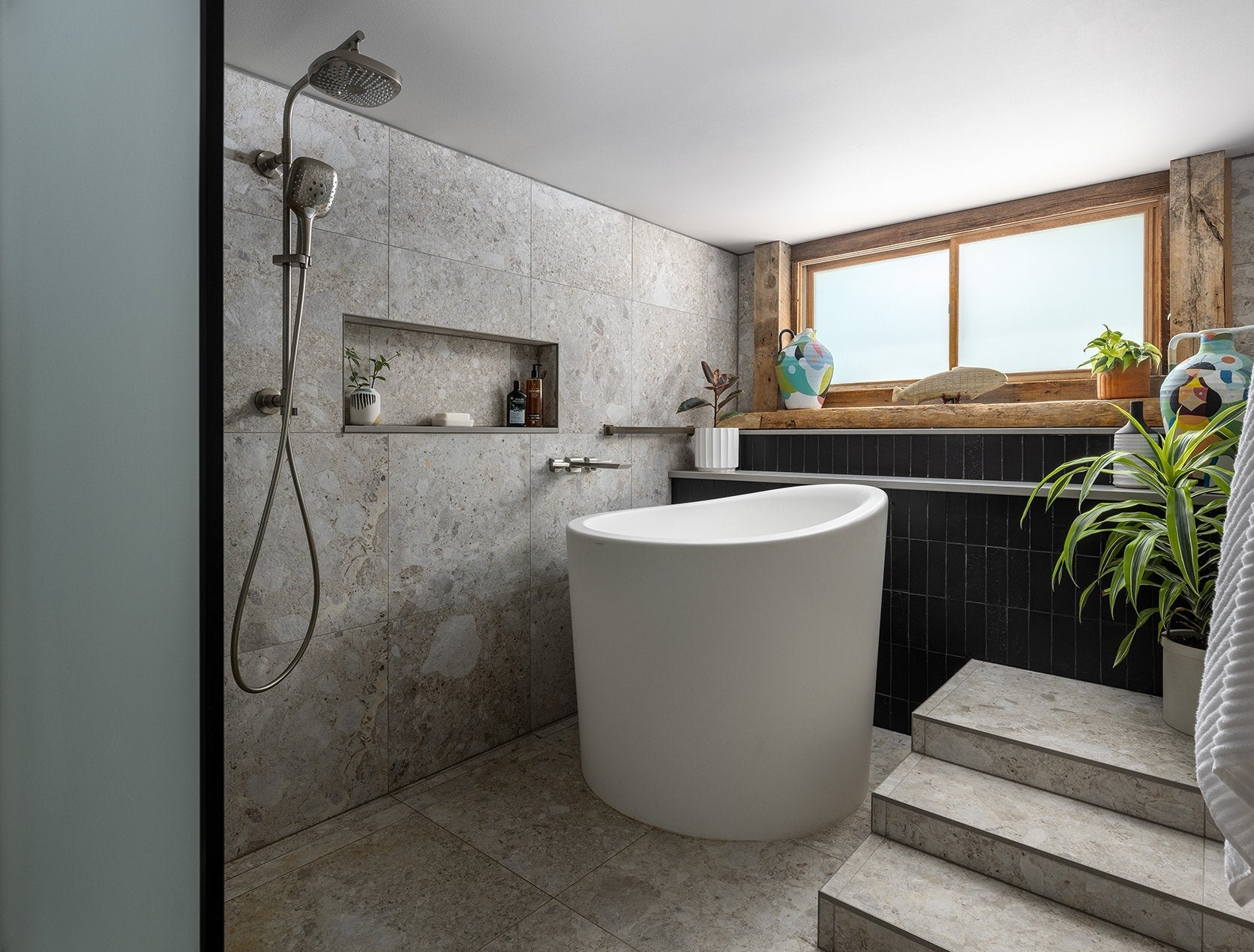 a stylish small freestanding bathtub, complemented by a minimalist bathroom design with natural light and greenery. | ACE DECOR