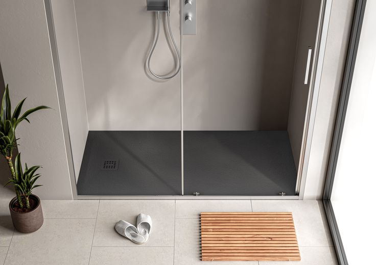 Modern walk-in shower with dark base, highlighting stylish sizes of shower bases.