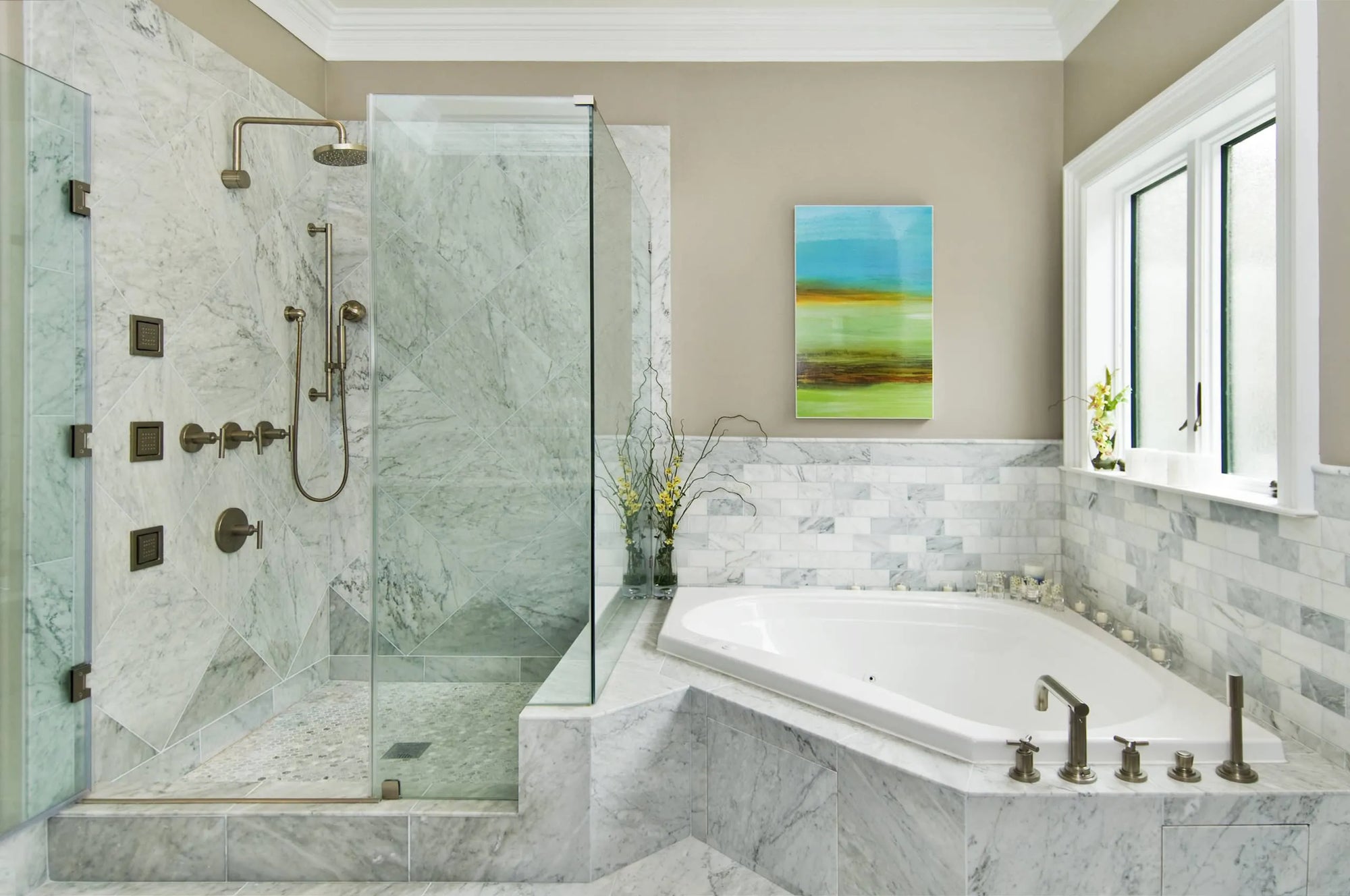 Luxurious bathroom with a corner bathtub, gold fixtures, white marble walls, glass shower, abstract art, and floral accents.