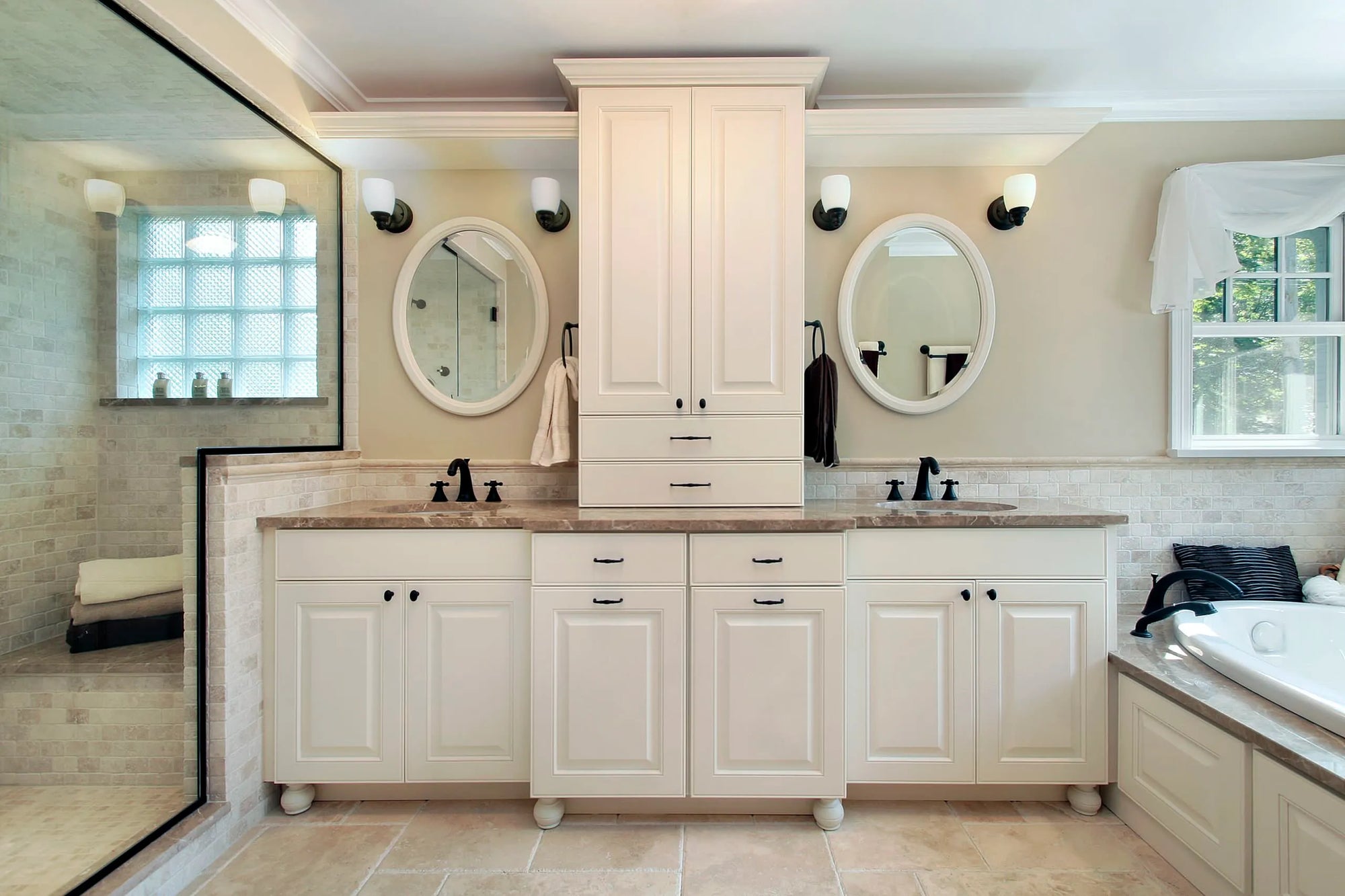 Luxurious bathroom with white wood bathroom cabinet, stone countertop, oval mirrors, black faucets, shower, and bathtub.