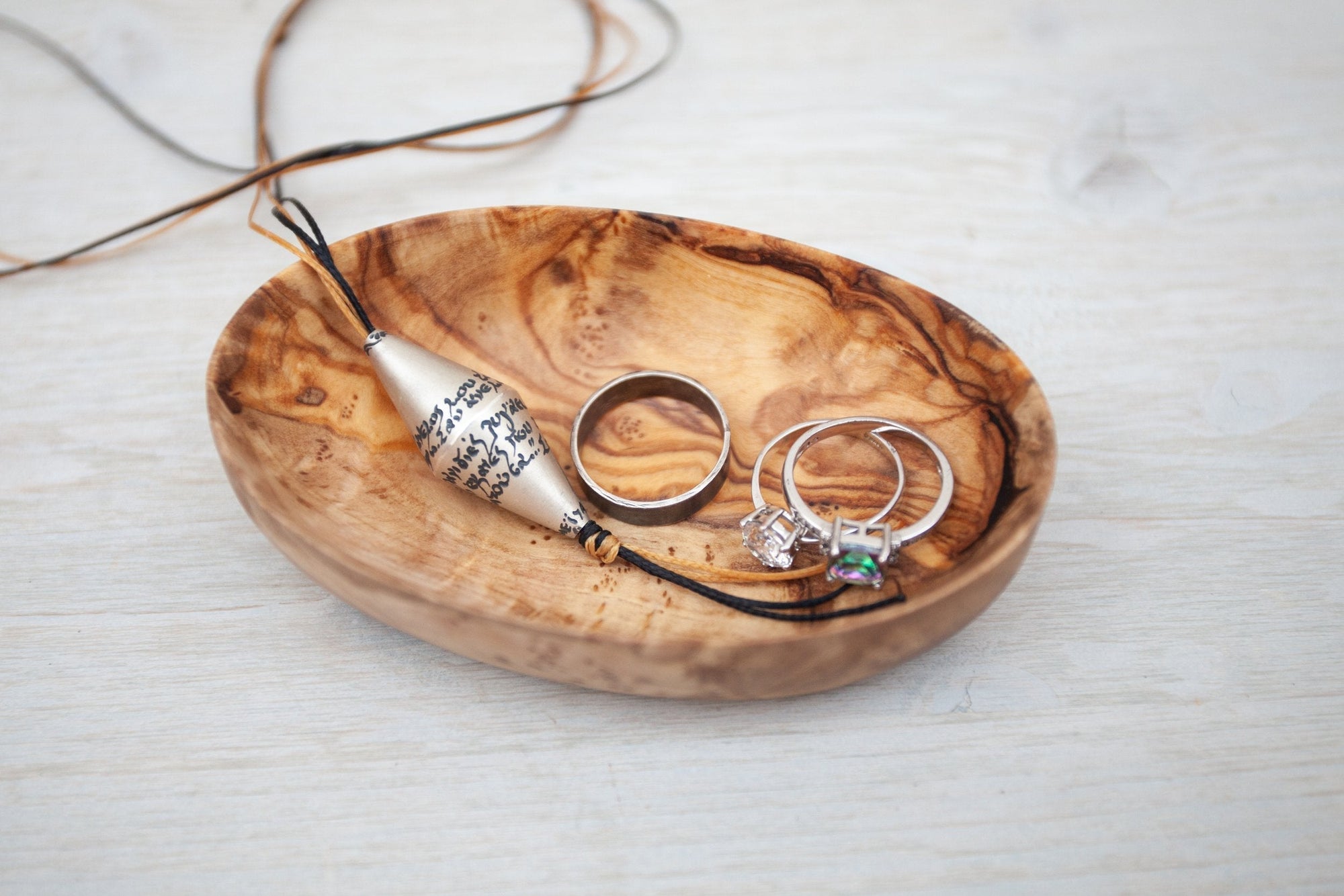 Oval wooden trinket dish holding rings and a pendant