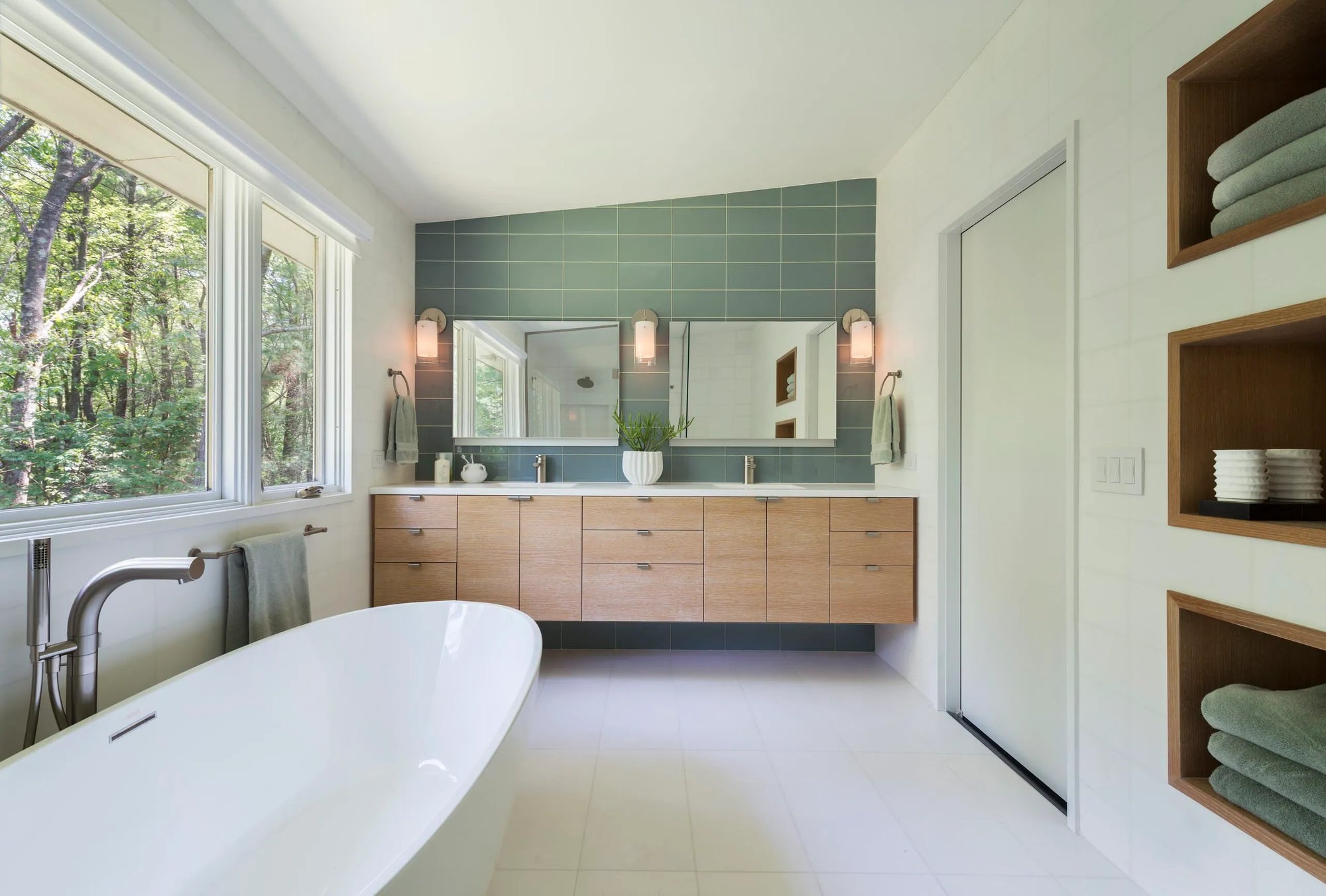 Modern bathroom with wooden vanity, built-in medicine cabinet, large mirror, and natural light.