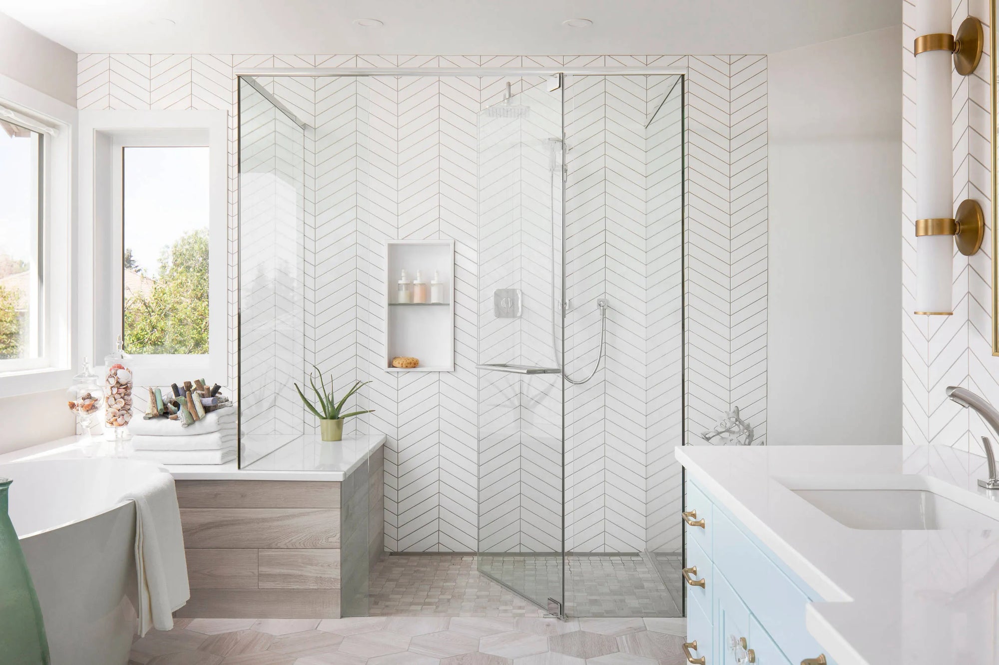 Shower room with glass enclosure, herringbone tile walls, hexagonal floor tiles, and freestanding bathtub.