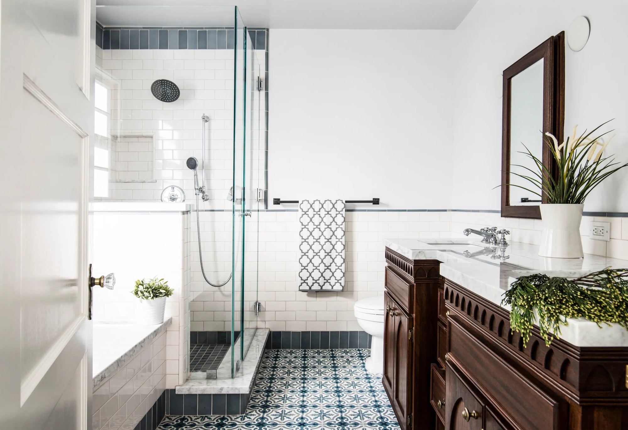 Modern bathroom with dark wood vanity, subway tile shower, and a framed bathroom mirror above the sink with green plants.