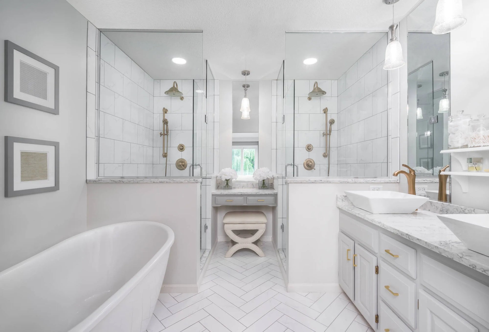 Modern bathroom with frameless shower door hardware, dual rain showerheads, freestanding tub, and double vanity in light gray and white tiles.