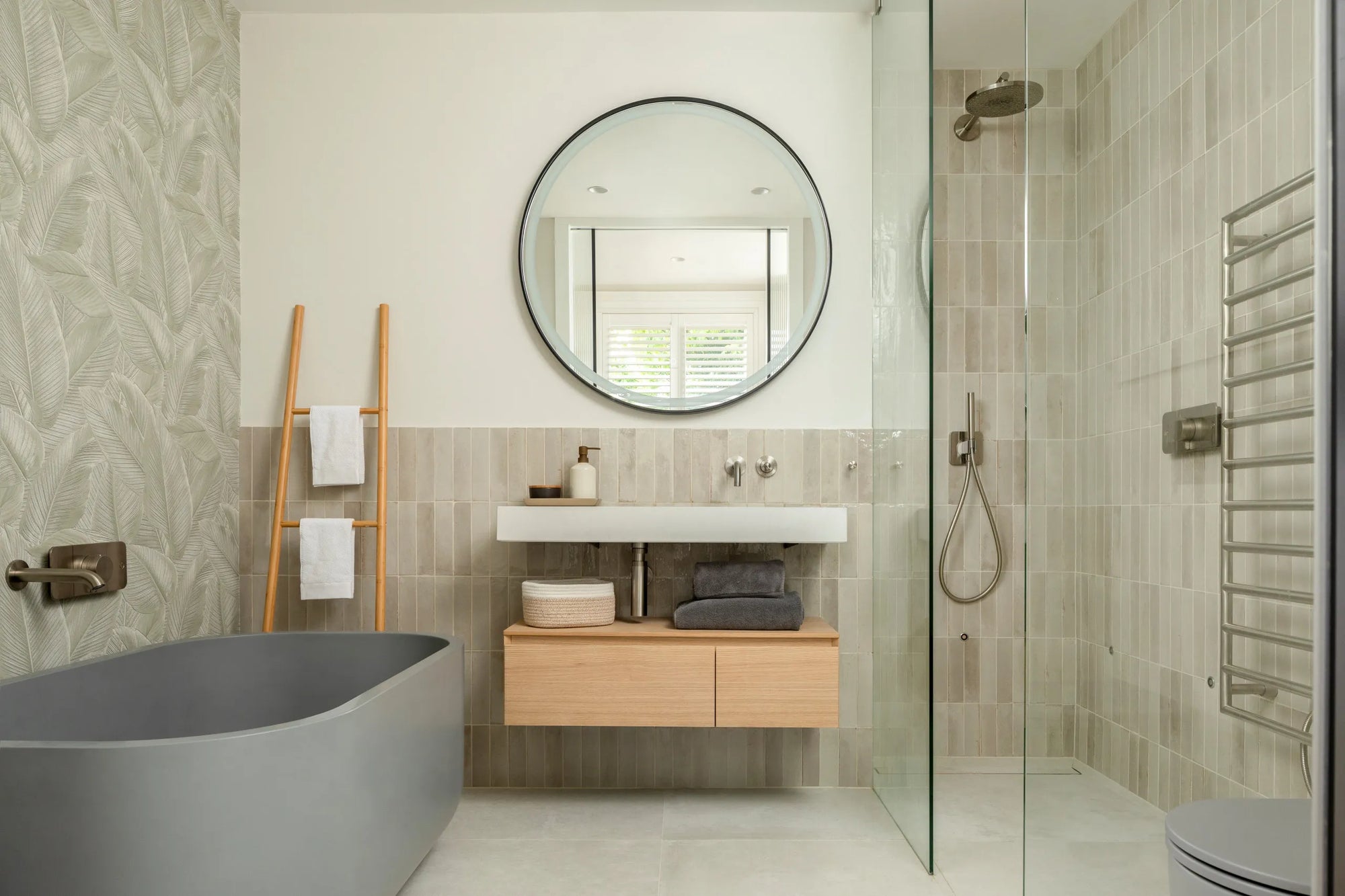 Modern bathroom interior with frameless shower door, freestanding soaking tub, light wood accents, and clean design.