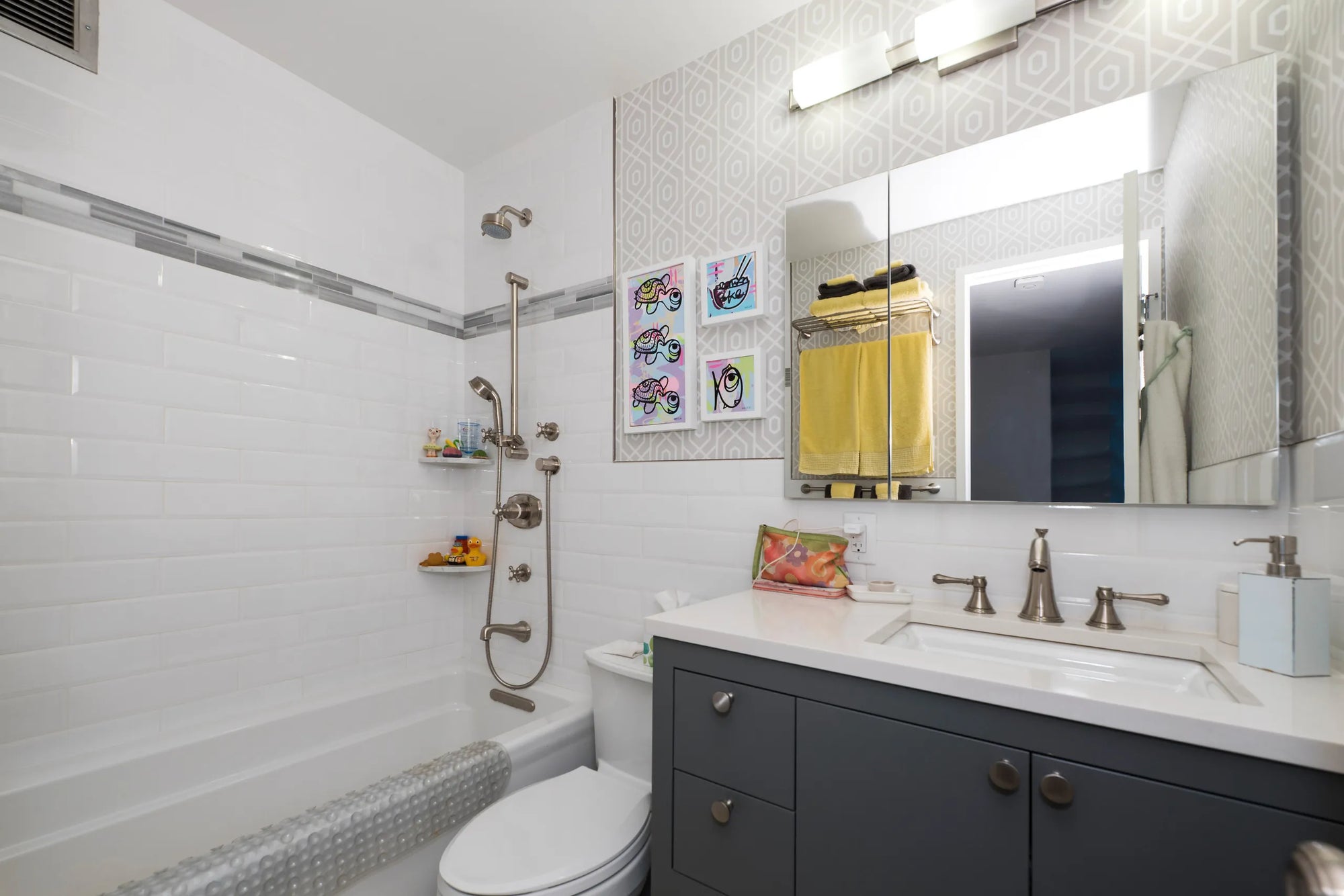 Modern small bathroom sink with nickel faucets, white countertop, grey cabinetry, large mirror cabinet in brilliantly lit compact space.