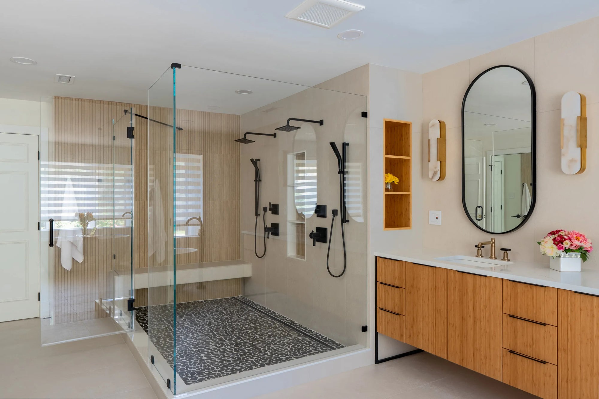 Modern black wall-mounted towel rack with neatly folded and rolled gray towels on a shelf with integrated LED lighting in a minimalist bathroom.