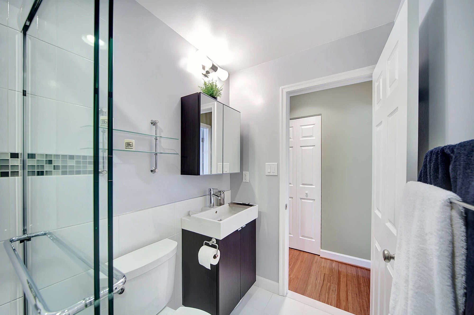 Modern bathroom medicine cabinet with mirrored doors above a white sink and dark brown vanity.