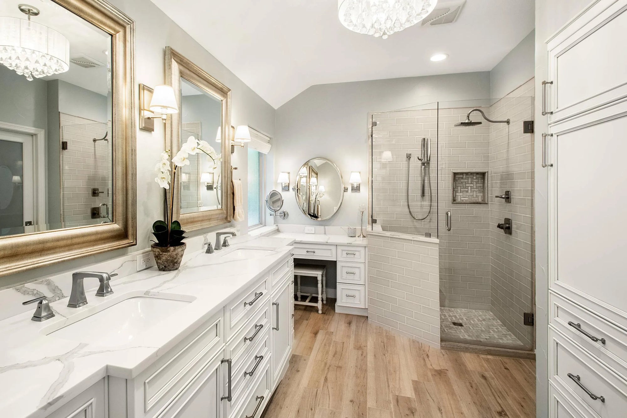 Modern bathroom vanity with makeup station featuring double sinks, framed mirrors, and elegant lighting.