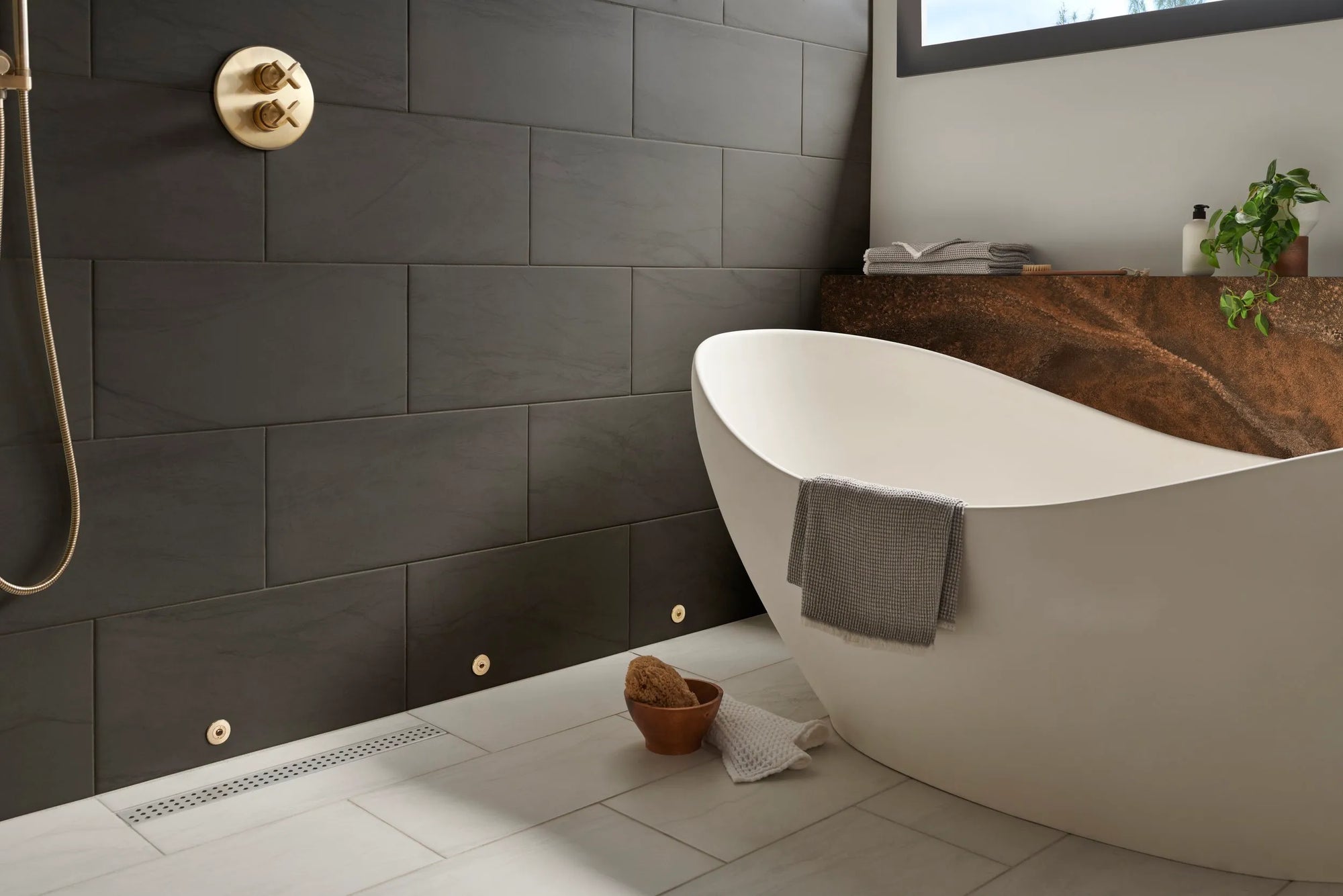 Modern bathroom featuring a sleek freestanding bathtub with a shower drying system, dark tiled walls, and minimalist design for ultimate relaxation.
