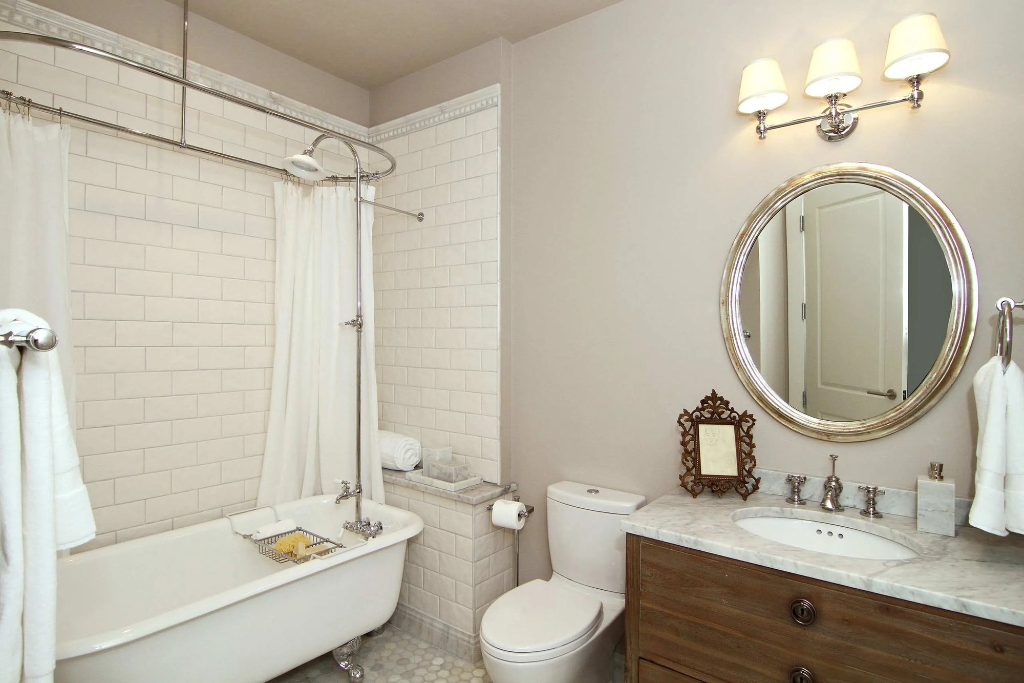 Clawfoot tub with a shower curtain in a vintage bathroom with subway tiles and pedestal sink.