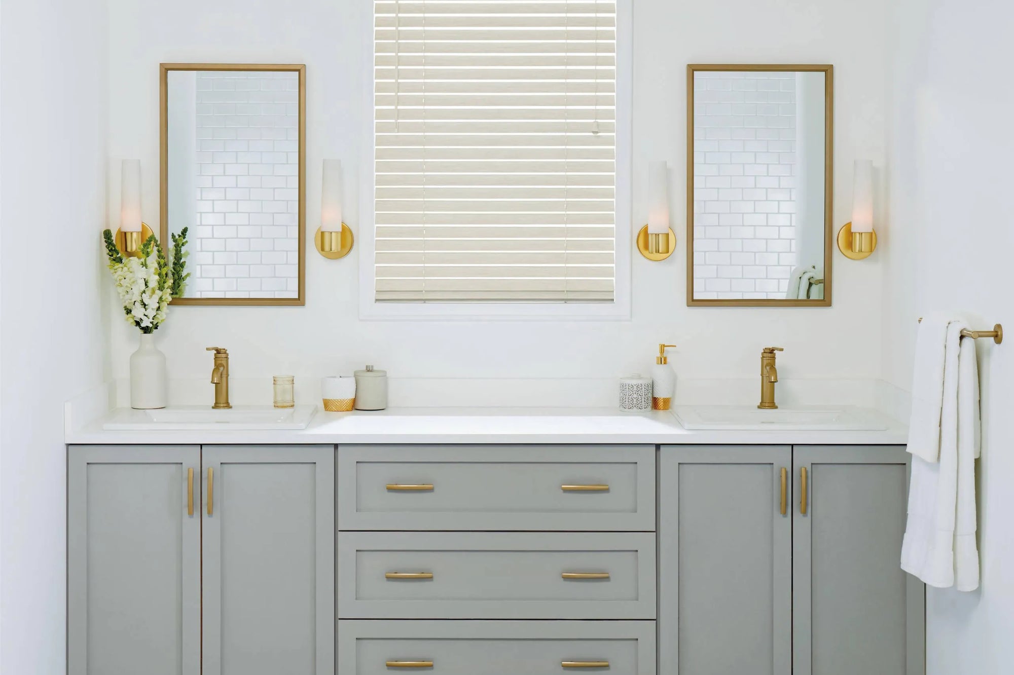 Modern bathroom vanity with two gold bathroom mirrors above a double sink, gray cabinets, and gold accents.