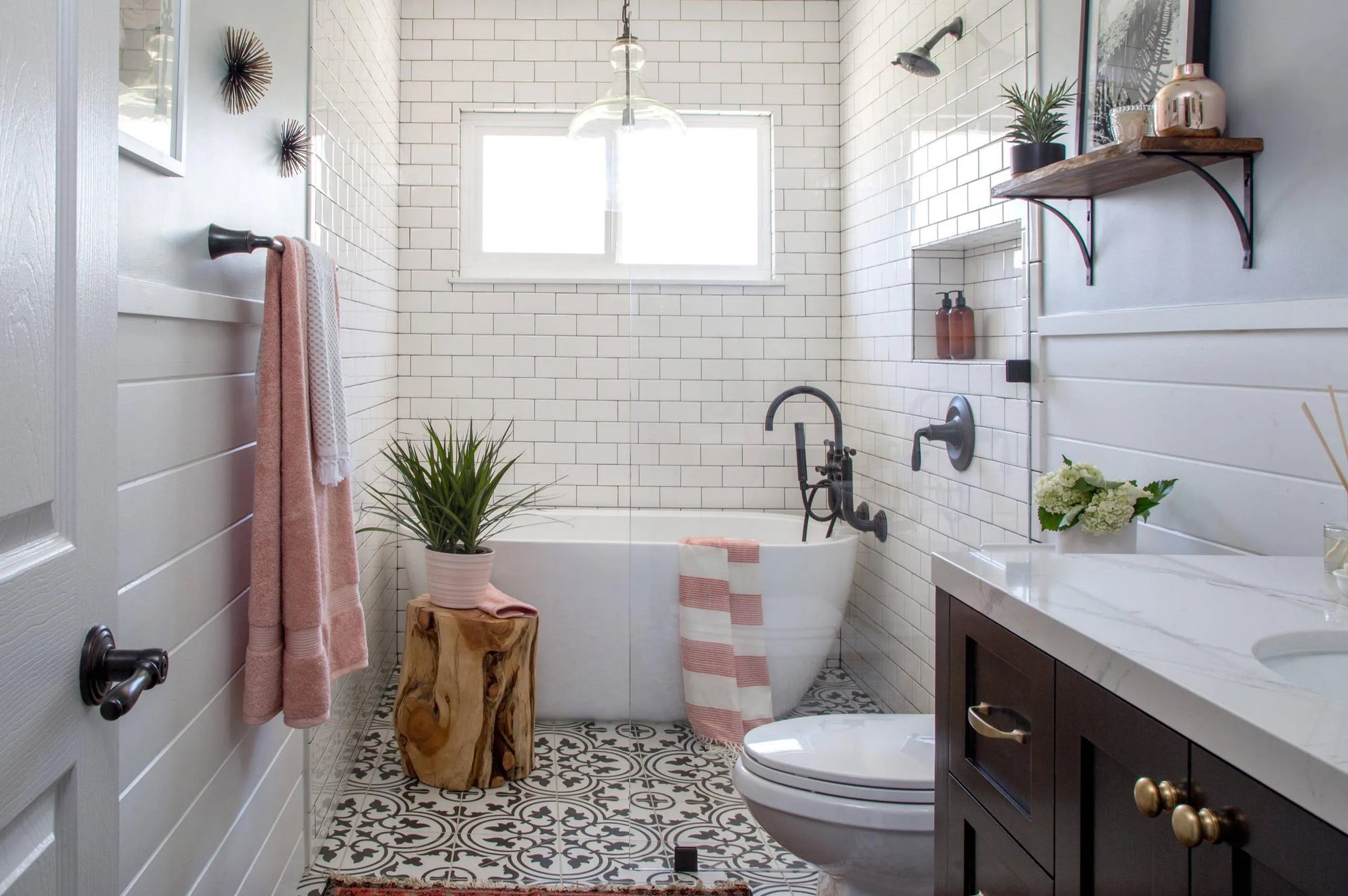 Modern bathroom featuring a freestanding bathtub with a black bathtub faucet, white subway tiles, and black-and-white floor tiles.