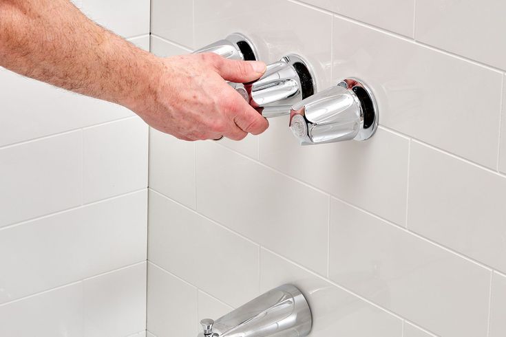 Step showing how to replace bathtub faucet by removing old chrome handles for repair or upgrade in bathroom.