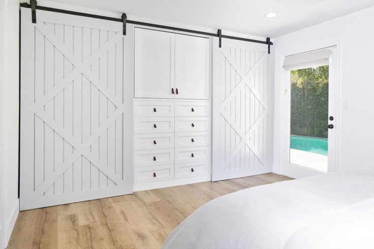 Barn doors for closets with a white farmhouse design, providing a stylish and functional solution for closet storage in a modern bedroom