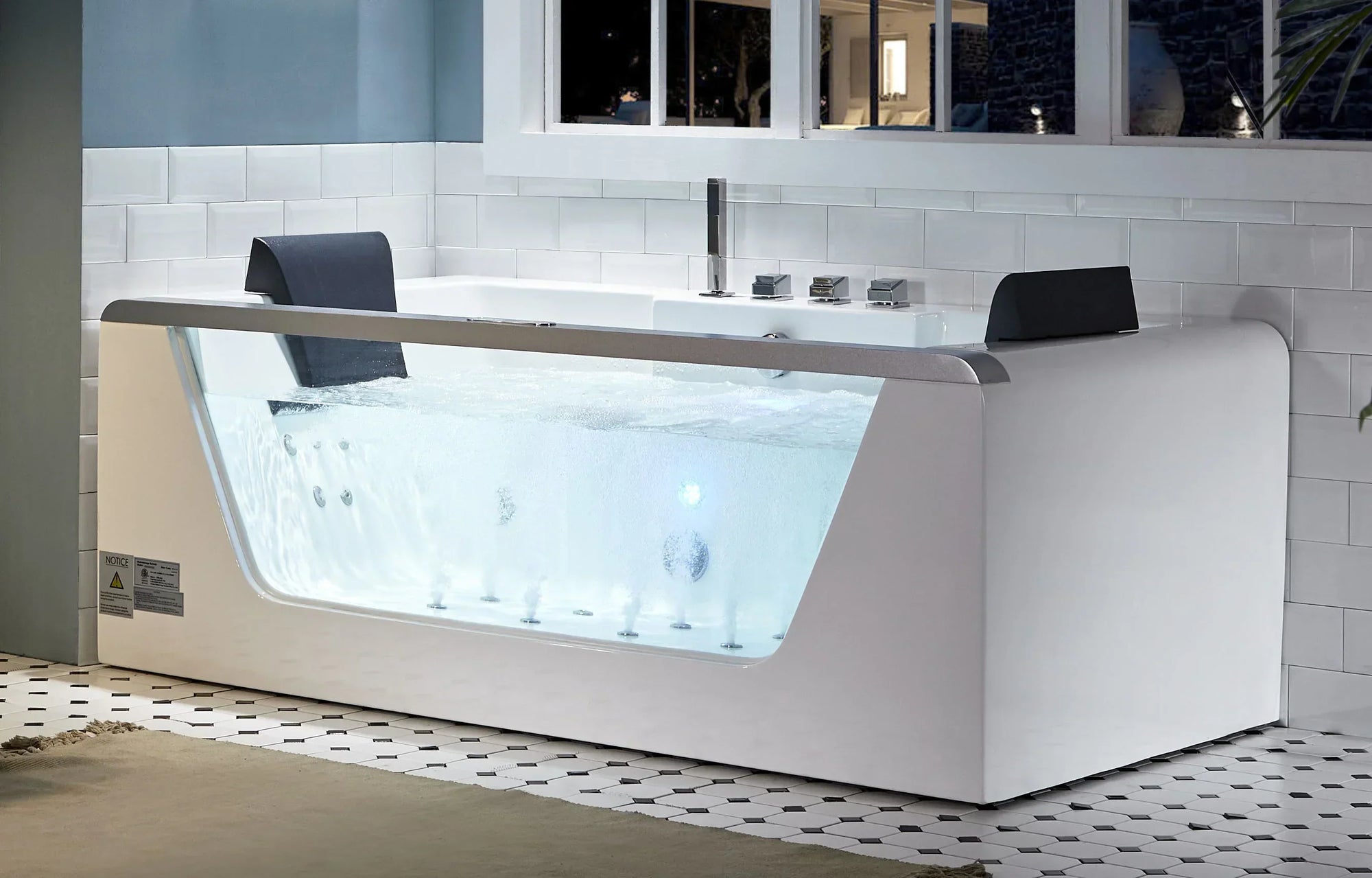 Modern white whirlpool bathtub with transparent front panel showcasing bubbling water jets, sleek design, silver faucet, and tiled bathroom setting.