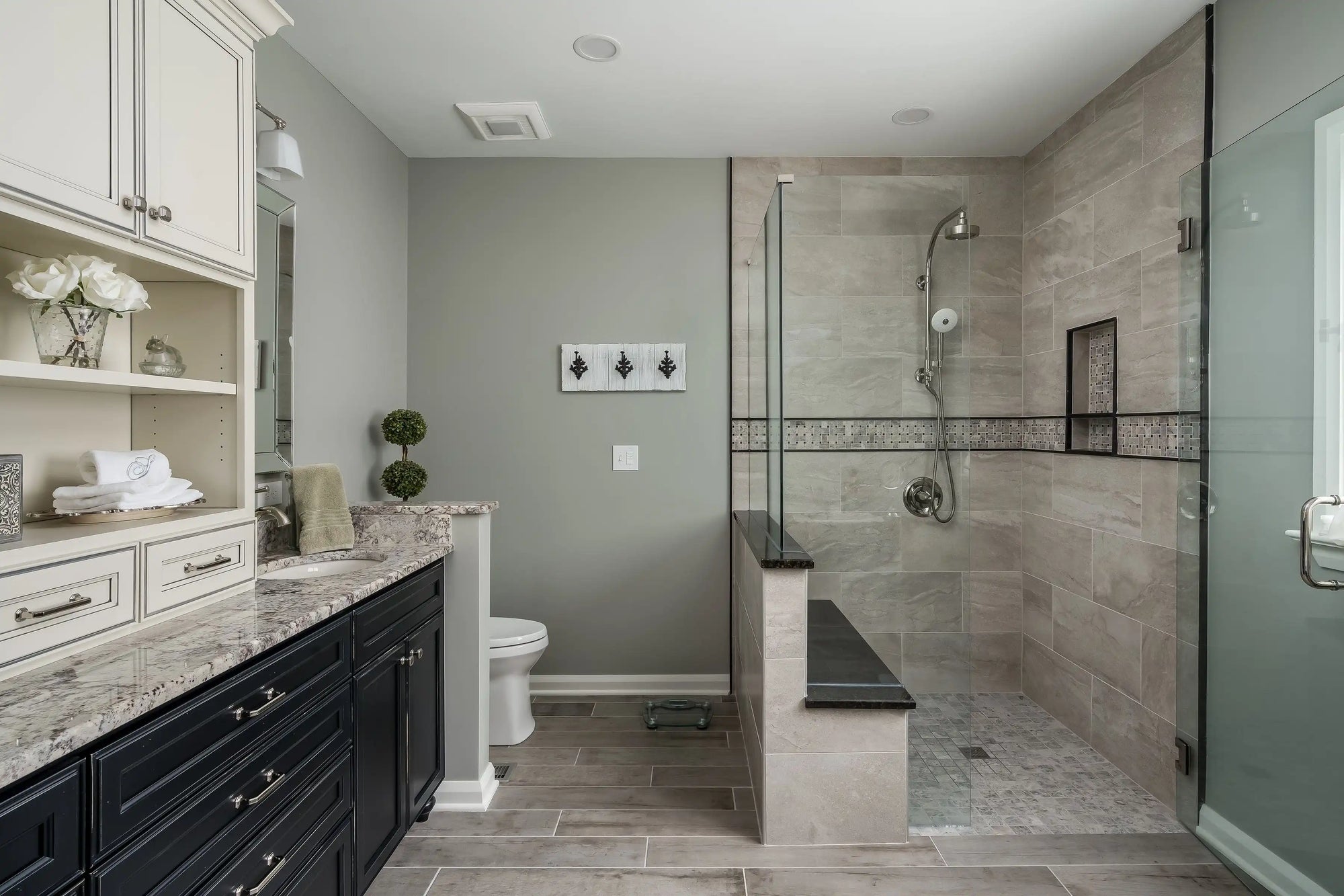 Elegant walk in shower with frameless glass shower doors and built-in bench in a neutral-toned bathroom