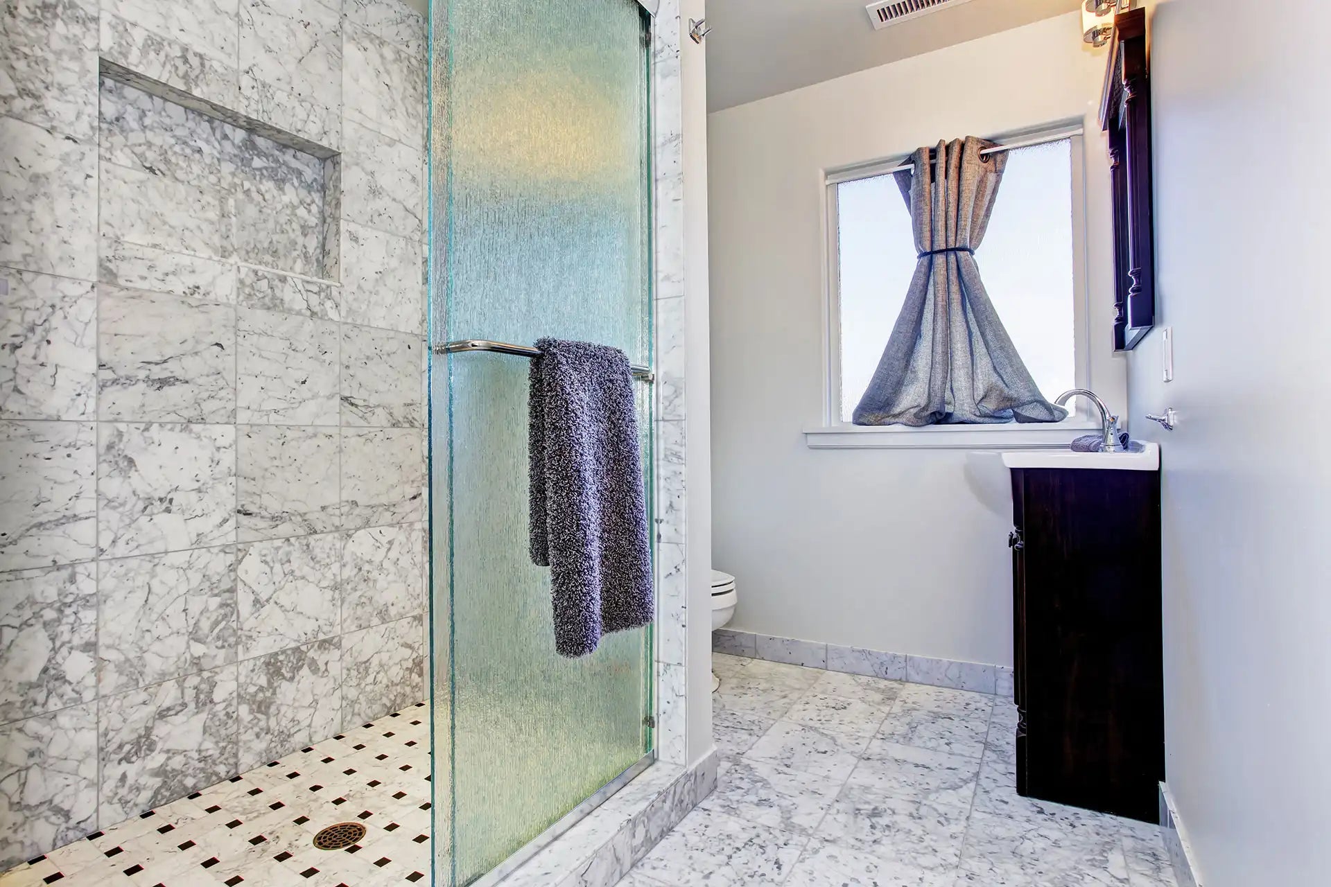 Classic white granite shower with glass door and matching granite tile flooring