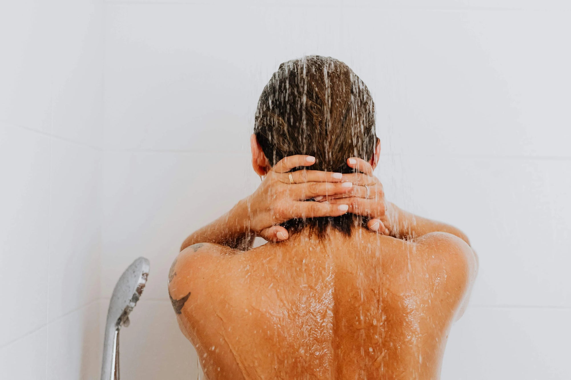 Person enjoying a refreshing shower with water flowing from a modern shower head.
