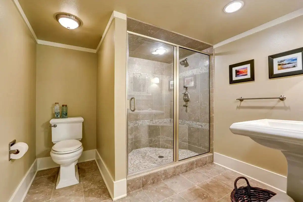 Corner bathroom with framed shower door glass sliding and stone-tile walls