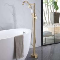 Brushed Gold Freestanding Tub Faucet with Handheld Shower Installed Beside Modern Freestanding White Bathtub.