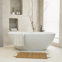 Aura Series stone resin 55" freestanding tub in a minimalist setting with built-in shelves and natural accents. |ACE DECOR