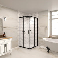 Corner black framed double sliding glass shower enclosure in a modern bathroom setting with white tile walls and freestanding bathtub.