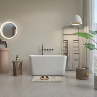Nectar Series 49"x28" White Acrylic Freestanding Soaking Tub in a modern bathroom with a bath mat, round mirror, and towel rack.