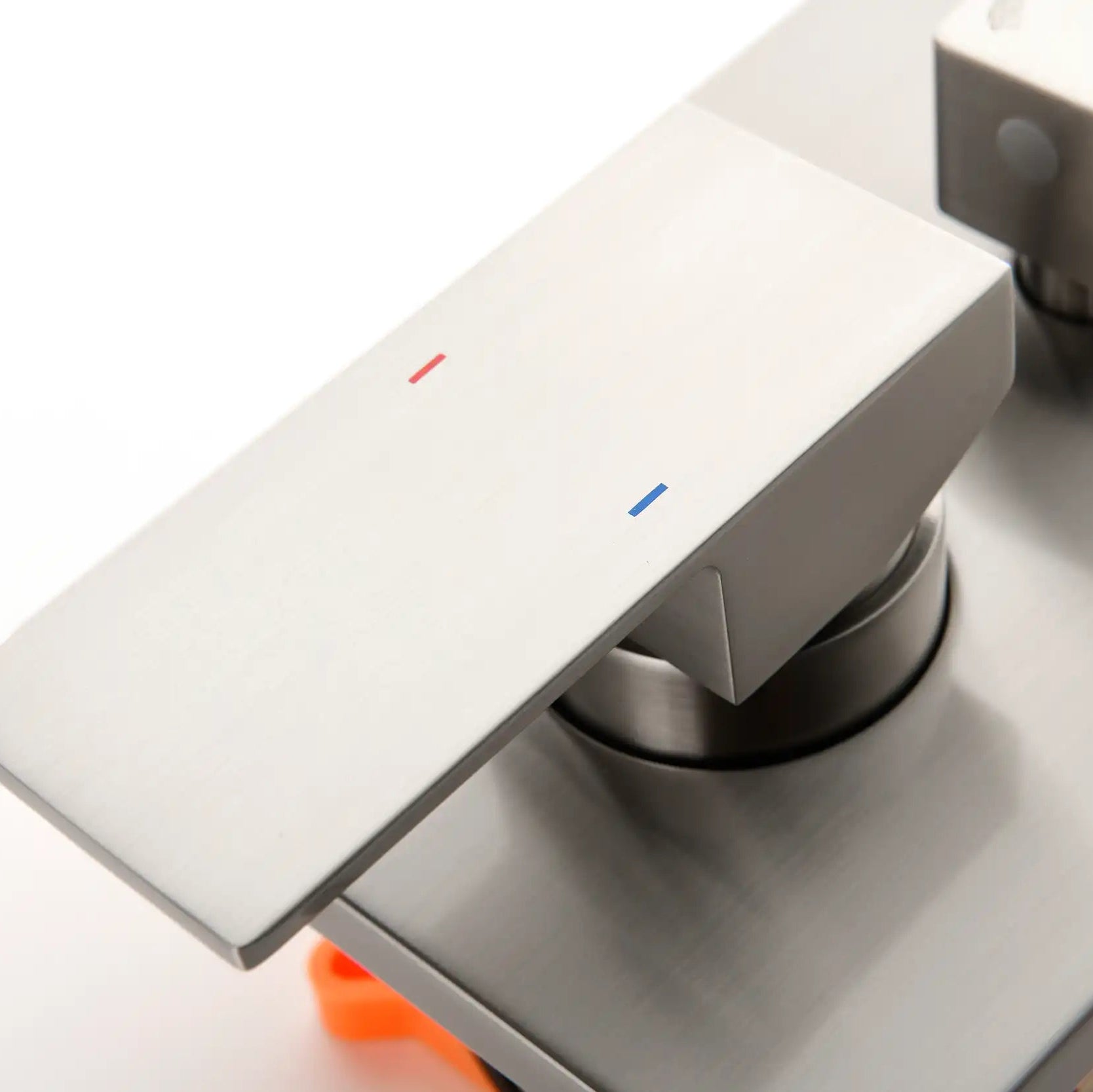 Brushed nickel shower temperature control handle with hot and cold indicators.