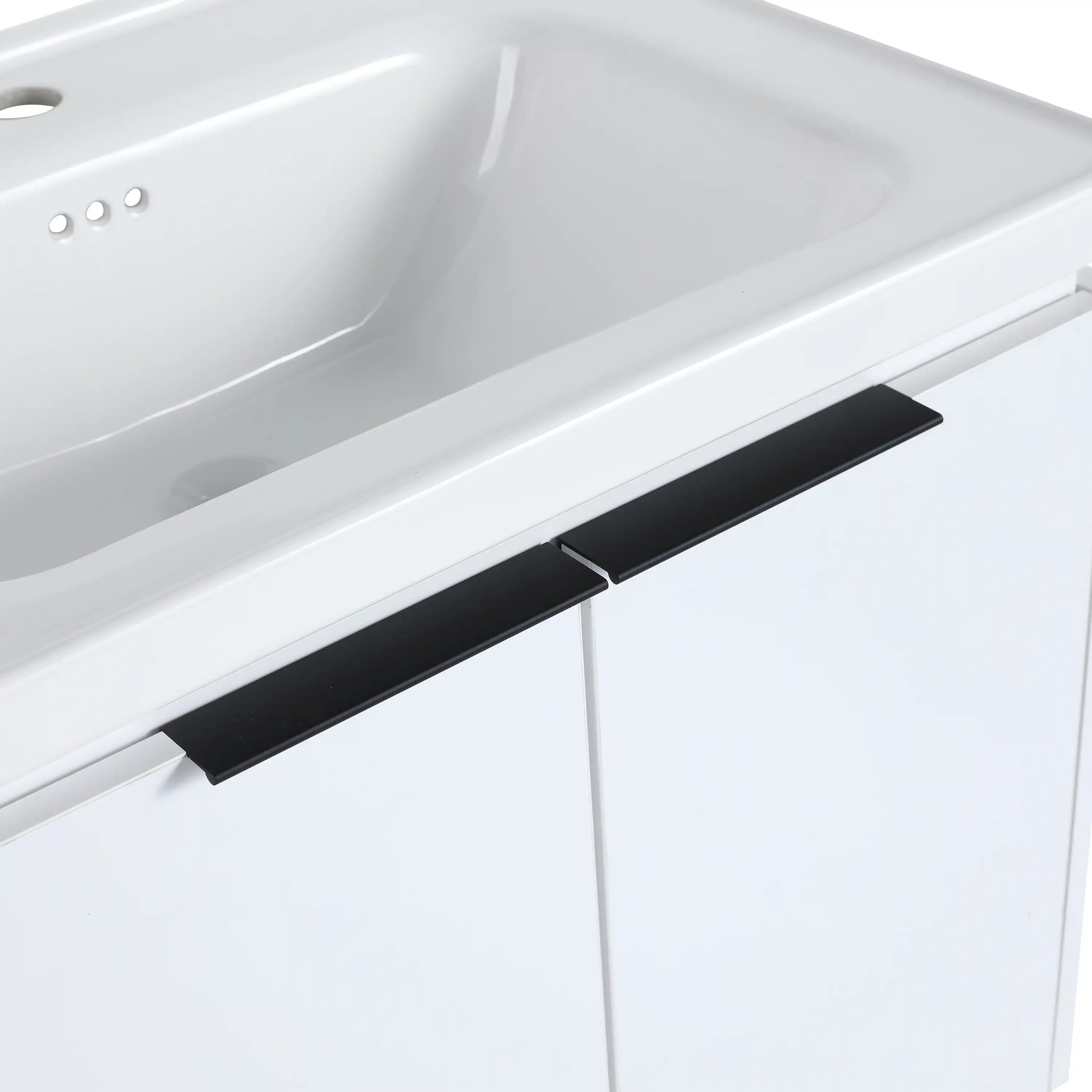 24 inch wall mounted vanity close-up of matte black handle and ceramic sink edge.