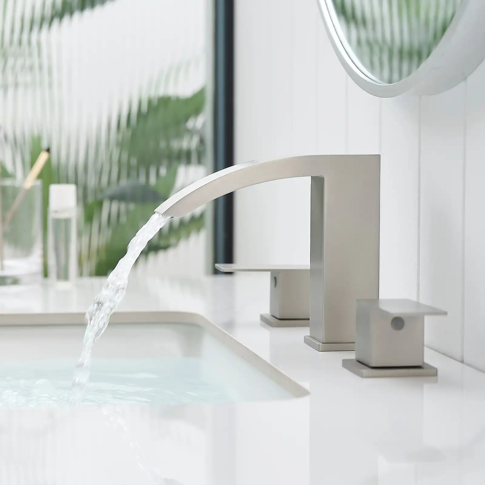 Modern waterfall bathroom faucet with sleek brushed nickel finish on white vanity countertop