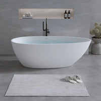 Abyss Series 59-inch egg-shaped resin stone freestanding tub filled with water in a serene bathroom with shelf and cactus decor.