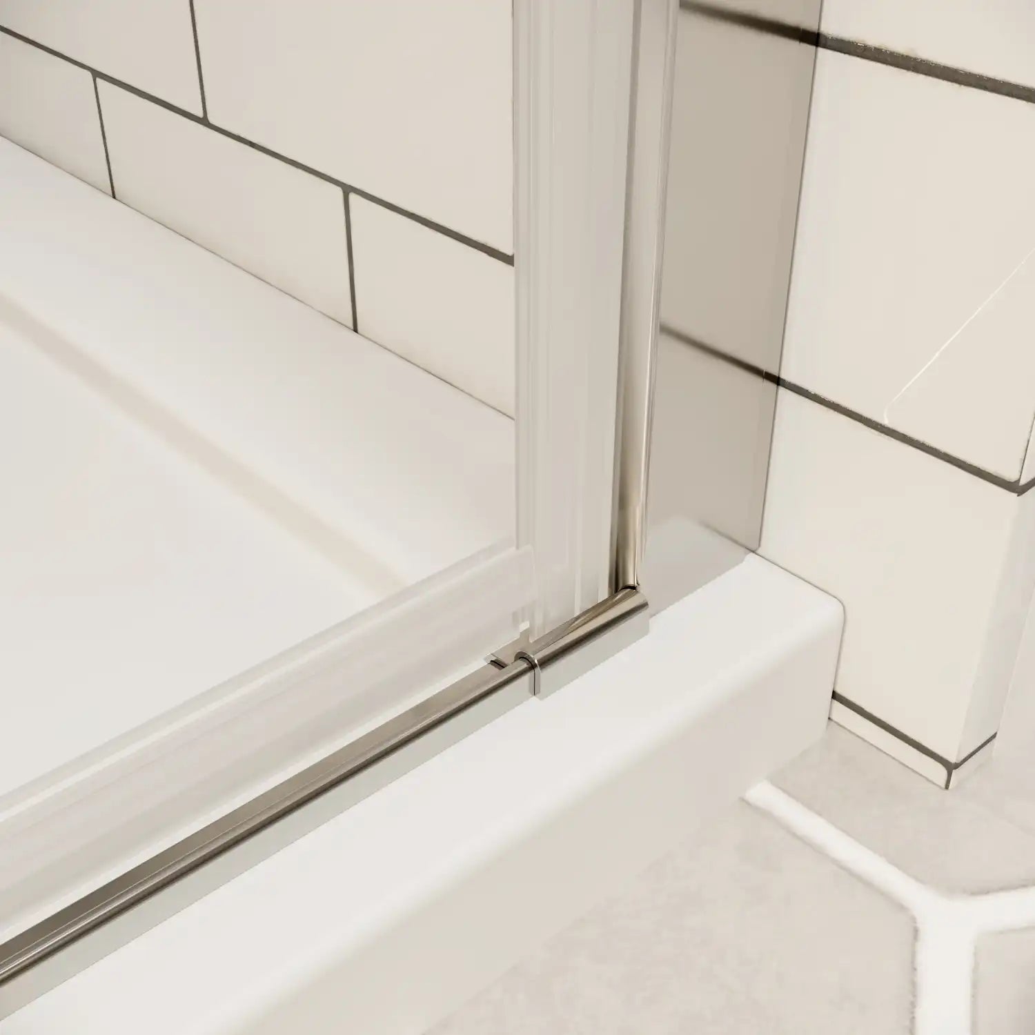 Chrome bottom track and seal detail on framed shower door over white shower base | Ace Decor