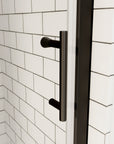 Matte black shower door handle on clear glass with white subway tile background | Ace Decor