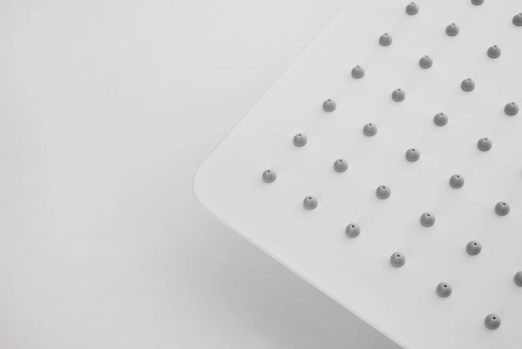 Close-up view of a square white shower head with self-cleaning silicone nozzles.