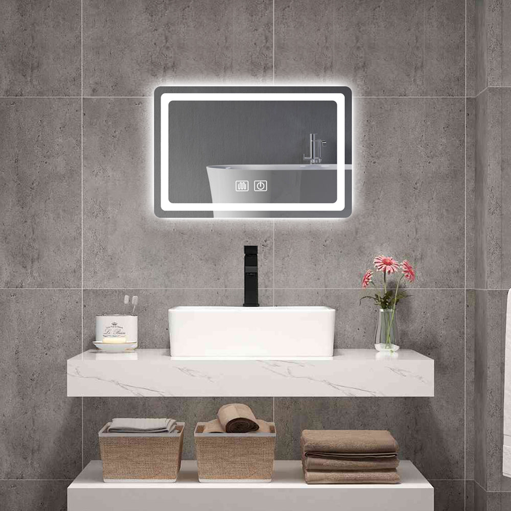 A stylish bathroom vanity setup featuring a floating sink and a rectangular mirror with LED lights for bathroom mirror use, glowing elegantly against matte stone tiles.
