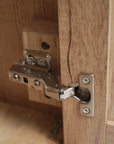 Close-up of metal hinge on bathroom vanity cabinet door, designed for smooth and silent operation | Ace Decor
