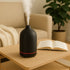 Brume 7 inch ceramic ultrasonic aromatherapy diffuser with soft mist on living room coffee table.